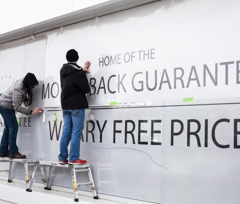two people hanging graphic display on wall